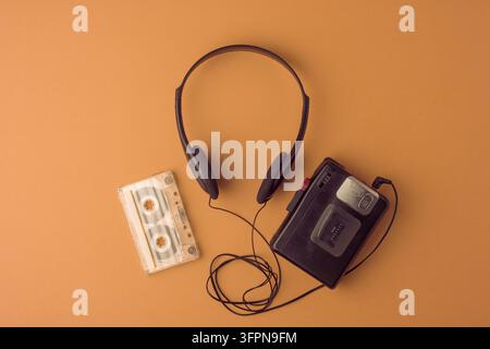 Klassischer Kassettenspieler, Kopfhörer und Band auf braunem Hintergrund wecken warme Erinnerungen an die 90er. Großer Kopierraum für jedes Projekt. Stockfoto