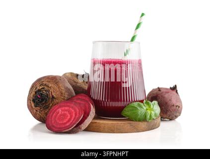 Rüben Saft in einem Glas mit einem gestreiften Papierstrohhalm, serviert mit roher Rübe und frischen Basilikumblättern isoliert auf weißem Hintergrund. Stockfoto