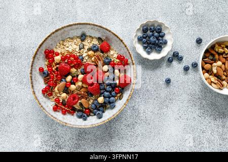 Gesunde Frühstücksschüssel mit Haferflockenmüsli, frischen Beeren, Himbeeren, Blaubeeren, Nüssen und roten Johannisbeeren Stockfoto