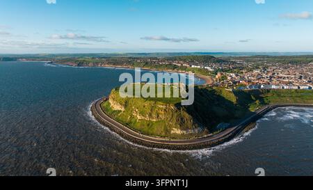 Luftaufnahme von Scarborough Castle, das auf einer markanten Landzunge mit Blick auf die Nordsee liegt, während die Küstenstadt Scarborough im Hintergrund zu sehen ist, S Stockfoto