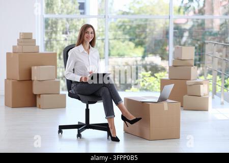 Frau mit Klemmbrett und Kartons im Raum. Büromiete Stockfoto