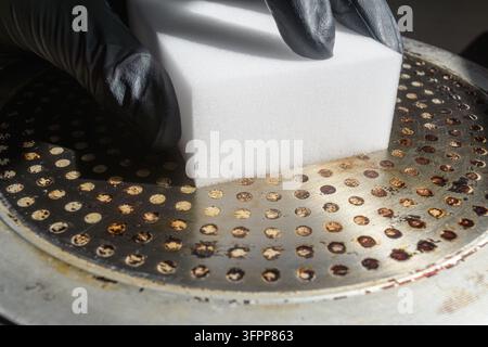 Melamin-Schwamm entfernt verbrannte Rückstände vom Bratpfannenboden und zeigt praktische Küchenreinigung und -restaurierung zu Hause. Stockfoto