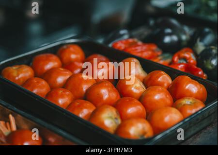 Ansicht von frischen roten Tomaten, die in einer schwarzen Plastiktray auf einem lokalen Markt in Puerto Viejo de Talamanca, Provinz Limon, Costa Rica angeordnet sind. Stockfoto
