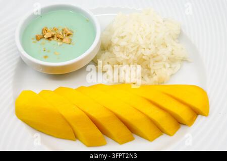 Asiatische Küche. Klassisches thailändisches Mango-Nudeln-Dessert mit Kokoscremesauce auf schwarzem Teller. Stockfoto