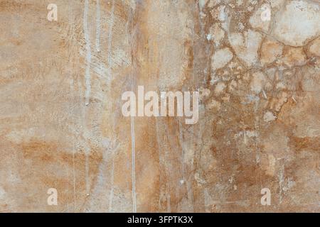 Warmer Ocker und Karamellbrauner Putzwand mit weißen Tropfenlinien und rissigen, schlammähnlichen Flecken, erdiger Lehmziegel-Stil Oberfläche Stockfoto
