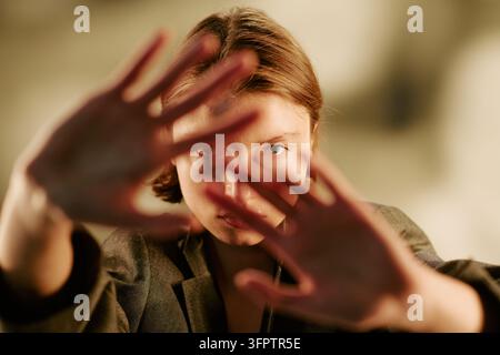 Porträt einer Frau, die die Kamera im Studio mit den Händen abdeckt Stockfoto