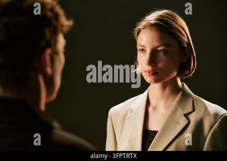 Ernste Frau schaut direkt auf den Mann während eines Studioshootings Stockfoto
