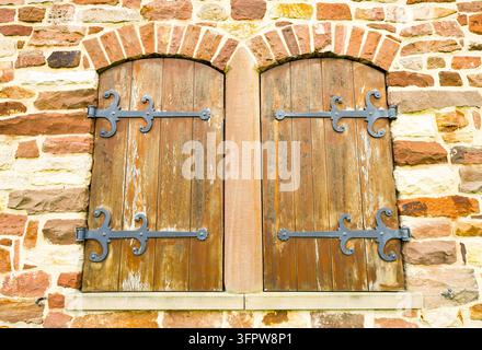 Rustikale Holzfenster mit Beschlägen an einer alten Ruine. Stockfoto