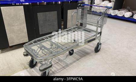 Großer metallener Flachbett-Einkaufswagen mit Drahtkorb zum Transport von sperrigen Waren in einem Baumarkt Stockfoto