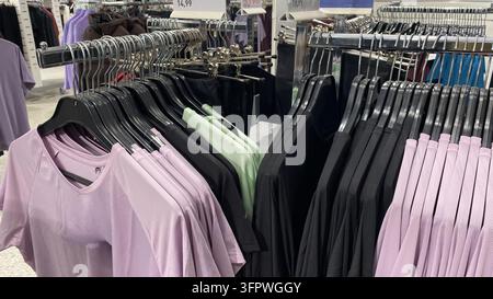Bunte Sportbekleidung und Sportoberteile, die auf Kleiderständern in einem Secondhand-Laden hängen Stockfoto