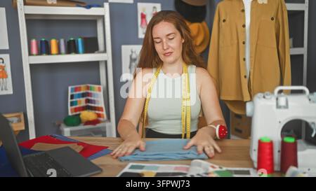 Damen Schneiderin glättet und faltet Stoff mit den Händen am Arbeitstisch neben der Nähmaschine im Studio; konzentrierte Kreativität. Stockfoto