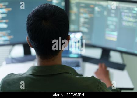 Programmierer codiert am Schreibtisch mit mehreren Computermonitoren Stockfoto