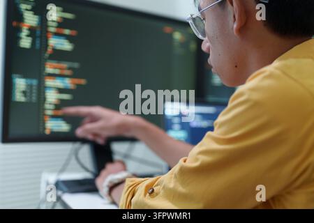 Mann mit Brille analysiert Code auf dem Computermonitor Stockfoto
