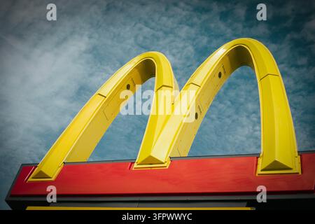 Niedrigwinklige Ansicht des ikonischen gelben McDonald's-Schildes vor bewölktem Himmel Stockfoto