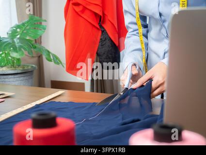 Schneiderin schneiden kleid Stoff auf Skizze Einklang mit der Nähmaschine. Fashion Designer anpassen oder Kanalsanierung in Workshop Studio entwerfen neue Kollektion Tuch Stockfoto