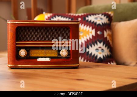Nostalgie und Retro-Lebensstil, altes Holzradio auf einem Tisch in einem gemütlichen Wohnrauminterieur mit verschwommenen gemusterten Kissen und warmer Wohneinrichtung Stockfoto