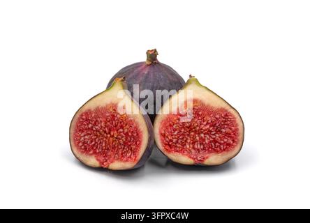 Zwei frische Feigenhälften mit saftigen roten Samen stehen vor einer ganzen reifen violetten Feige auf einem sauberen weißen Hintergrund. Stockfoto