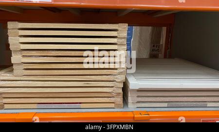 Stapel aus Holzlattenplatten in Natur- und Weißlackierung, in Schutzplastik eingewickelt, auf Regalen in einem Baumarkt Stockfoto