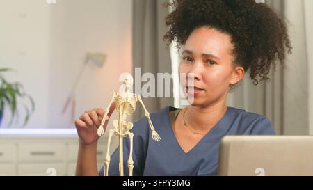 Arzt erklärt Anatomie mit einem Skelettmodell während einer Gesundheitsberatung Stockfoto