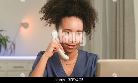 Lockenkopf-Krankenschwester telefoniert, während sie einen Laptop benutzt Stockfoto