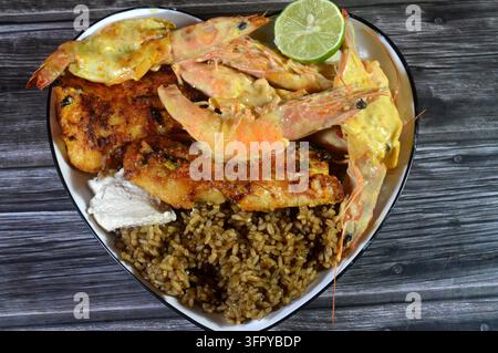 Ein Meeresfrüchteschmaus auf einem herzförmigen weißen Teller, mit gegrillten Fischfilets, ganzen Schmetterlingsgarnelen gekrönt mit einer cremigen Sauce, brauner Sayadieh Stockfoto