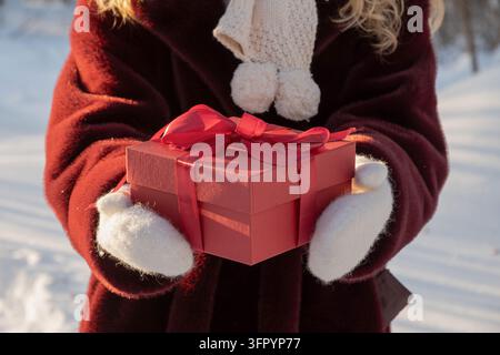 Weihnachtsgeschenkbox in weißen Handschuhen im Freien im Winter Stockfoto