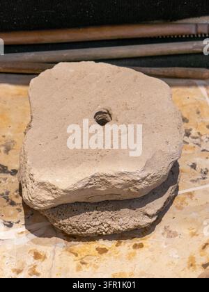 Alte handgeschnitzte Steinquernmühlen mit Mittelloch zum Mahlen von Getreide, ausgestellt in einer Museumssammlung. Stockfoto