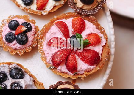 Erdbeer-Frucht-Tarte mit Sahne und Minze auf Teigboden. Süßer Dessert-Hintergrund für Bäckereileckerbissen, Sommerbeeren und Partyessen. Stockfoto