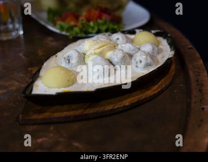 Traditionelle bosnische Fleischbällchen (Cufte) in einer reichhaltigen Rahmsauce mit gekochten Kartoffeln, serviert heiß in einer Gusseisenpfanne. Lokales Essen aus Sarajewo. Stockfoto