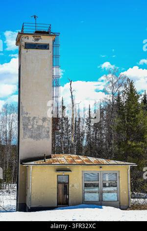 Ehemalte Feuerwache mit einem hohen SchlauchtrocknungsTurm in Murjek, Gemeinde Jokkmokk, Nordschweden, umgeben von Wald und Schnee. Stockfoto