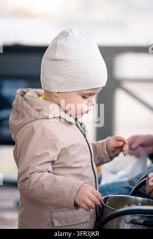 Kind und Großeltern bereiten gemeinsam geerntete Gemüse während der Herbstgartensaison und beim Kochen im Freien zu Stockfoto