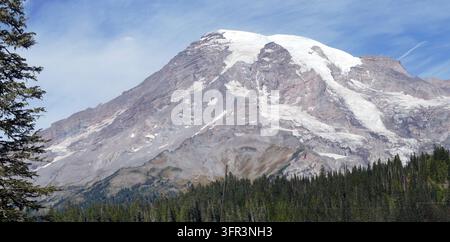 Mount-Rainier-Vulkan, der über immergrünen Wäldern aufragt und seinen schneebedeckten Gipfel und die Gletscherfelder in der Kaskadenkette zur Schau stellt. , Mount Rainier Stockfoto