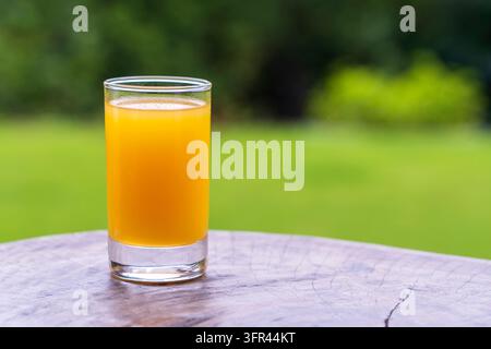 Glas mit tropischem Saft aus Mango und Passionsfrucht auf dem Holztisch im Hof, Nahaufnahme, Tansania, Ostafrika, Kopierraum Stockfoto