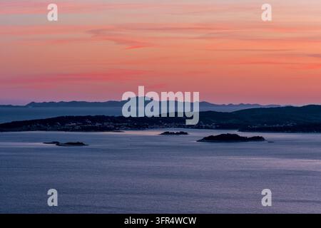Erhöhte Aussicht über das Meer in Richtung Orebić und die umliegenden Inseln, vor dem Hintergrund eines ruhigen Sonnenuntergangshimmels über der Küste. Stockfoto