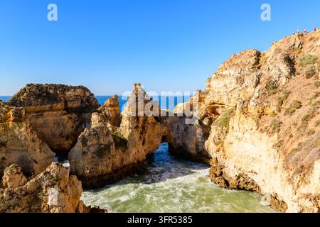 Felsformationen, Meeresbögen und Klippen säumen die Küste, mit blauem Himmel und Brandung. Stockfoto