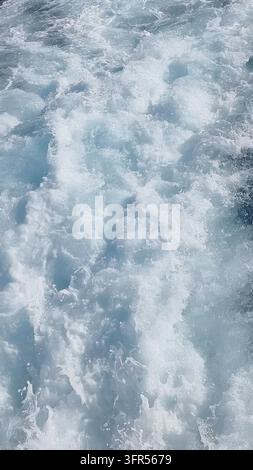 Weißer Seeschaum und türkisfarbenes Wasser als Texturhintergrund Stockfoto
