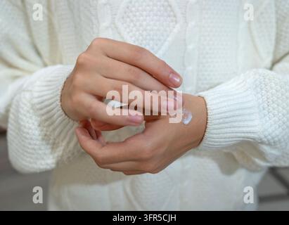 Nahaufnahme einer Frau, die feuchtigkeitsspendende Creme auf die Hand aufträgt, für die tägliche Hautpflege Stockfoto