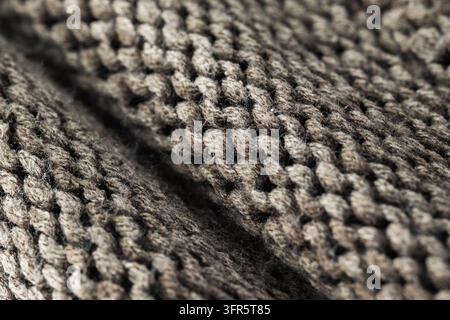 Makroaufnahme zeigt komplizierte gewebte Schlaufen und Textur eines braunen Strickstoffs, was Wärme und Komfort suggeriert Stockfoto