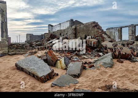 Winterstarker heftiger Sturm (Zyklon) zerstörte ein Steinhaus an einem Sandstrand. Die Mauer fiel unter der Kraft der zerstörerischen Wellen zusammen Stockfoto