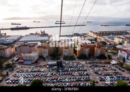 Ein Panoramablick auf Gibraltar mit Wohngebäuden, einem belebten Parkplatz, einem Yachthafen mit Yachten und zahlreichen Frachtschiffen vor Anker Stockfoto