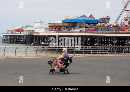 Blackpool, Lancashire, Vereinigtes Königreich – 26. Juni 2024: Frau fährt einen Mobilitätsroller vor dem zentralen Pier von Blackpool Stockfoto