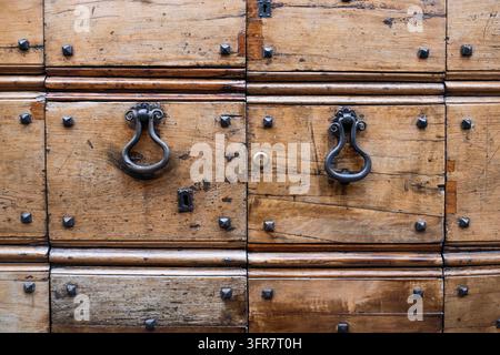 Nahaufnahme einer verwitterten Holztür mit dunklen Metallgriffen und sichtbaren Nieten, Gubbio, Umbrien, Italien Stockfoto
