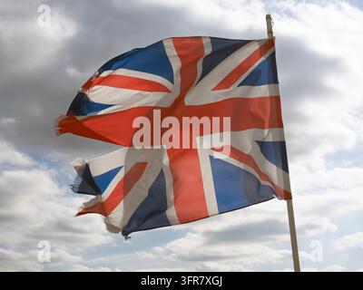 Zerfetzte britische Nationalunion-Flagge, die vor einem trüben Himmel weht Stockfoto