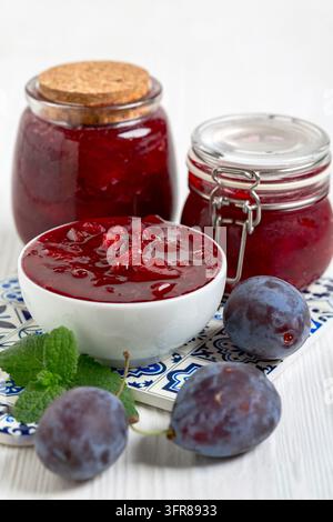 Gesunde Marmelade aus reifen Pflaumen in einem Gläser auf einem weißen Holztisch. Nährstoffreiches veganes Dessert. Hausgemachte Bio-Marmelade Stockfoto