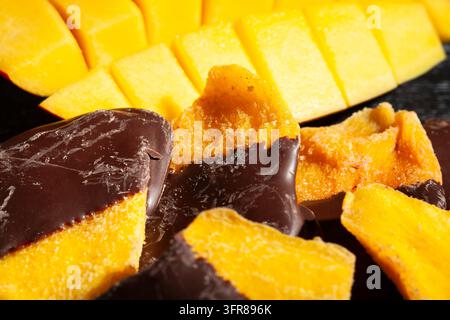 Schokoladengetaufter Mango auf schwarzem Holzgrund Stockfoto