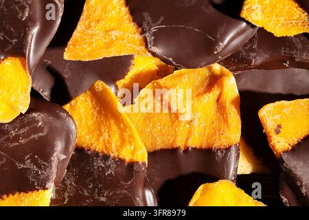 Schokoladengetaufter Mango auf schwarzem Hintergrund, Ansicht von oben Stockfoto
