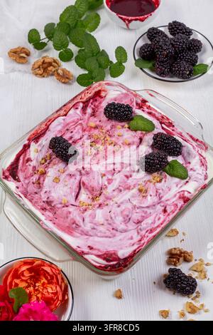 Hausgemachtes Brombeereis in einem Glasbehälter mit Brombeeren und Minzzweigen Stockfoto
