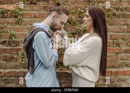 Ein fröhliches multikulturelles Paar in Warschau, Polen, genießt die gemeinsame Zeit. Paar vor einem rustikalen roten Ziegelhintergrund. Frau und Mann im Beauti Stockfoto
