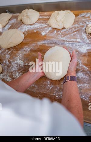 Personenhande formen einen Teigball auf einem bemehlten Holztisch, Brot backen, Haselstaller Hof, Wildberg, Schwarzwald, Deutschland Stockfoto