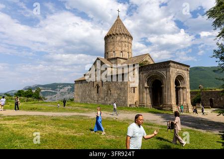 Fassade der Tatev-Klosterkirche mit vielen Touristen, die über das Gras davor gehen, Syunik-Provinz, Tatev, Armenien Stockfoto